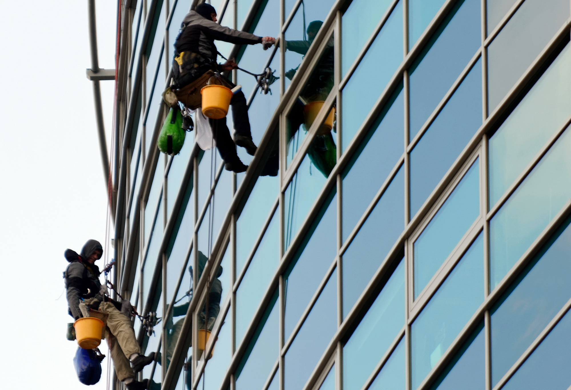 two window washers washing the exterior windows of a large building.